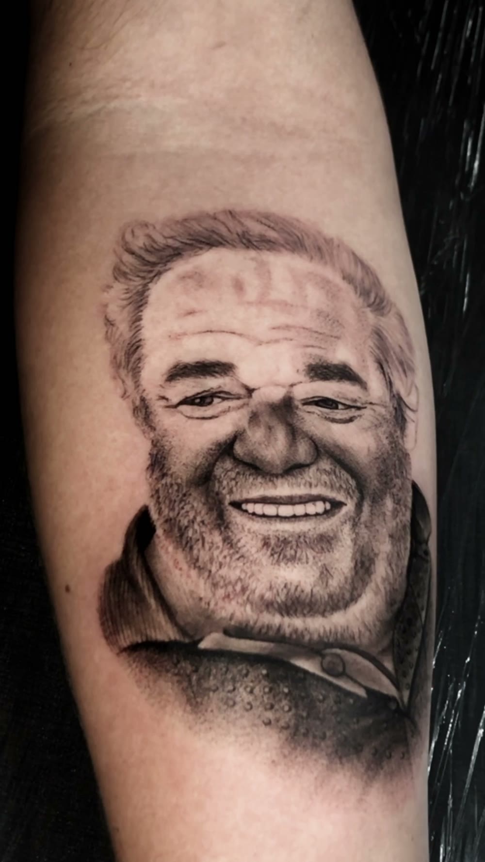 Tatuagem realista em preto e cinza, retrato no antebraço